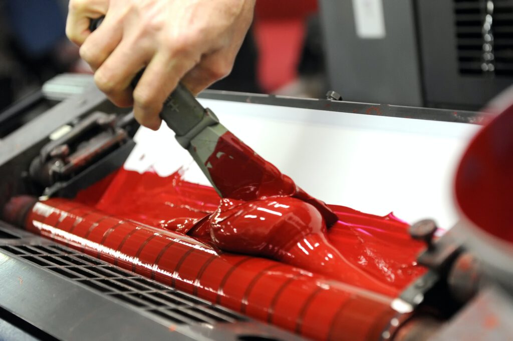Worker uses specialized spatula to apply red paint